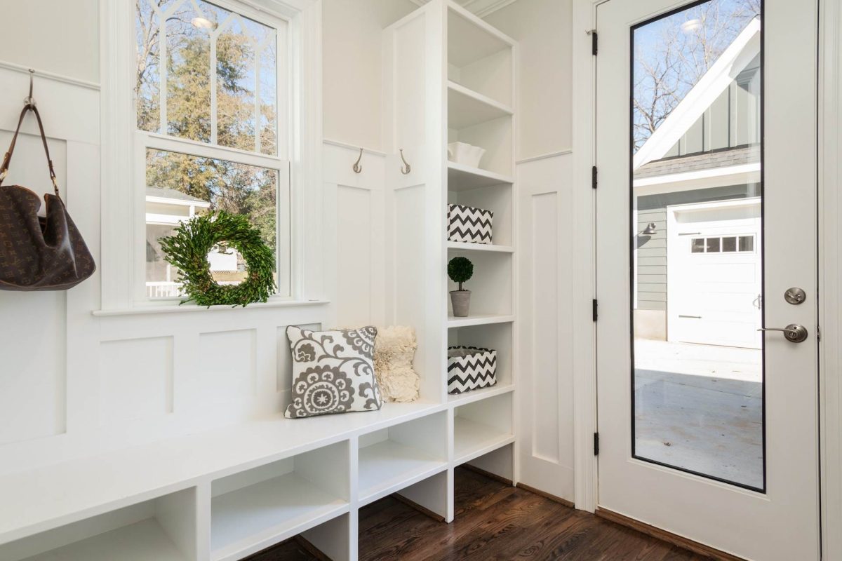 Mudroom in a new home with built-in shelving, bench seat, hooks, and natural light