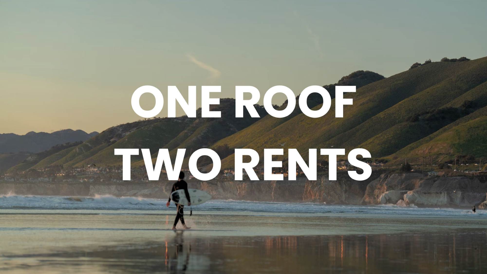 Surfer walking towards surf with green mountains and a cliff-edge town, "ONE ROOF TWO RENTS" text