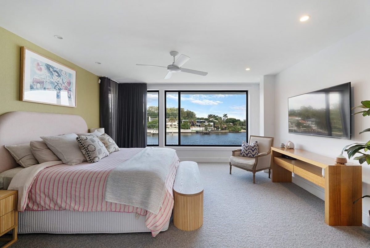 Master bedroom at 28 Kookaburra Court, Sorrento, with large bed, chair, media stand, wall-mounted TV, and canal views through large windows