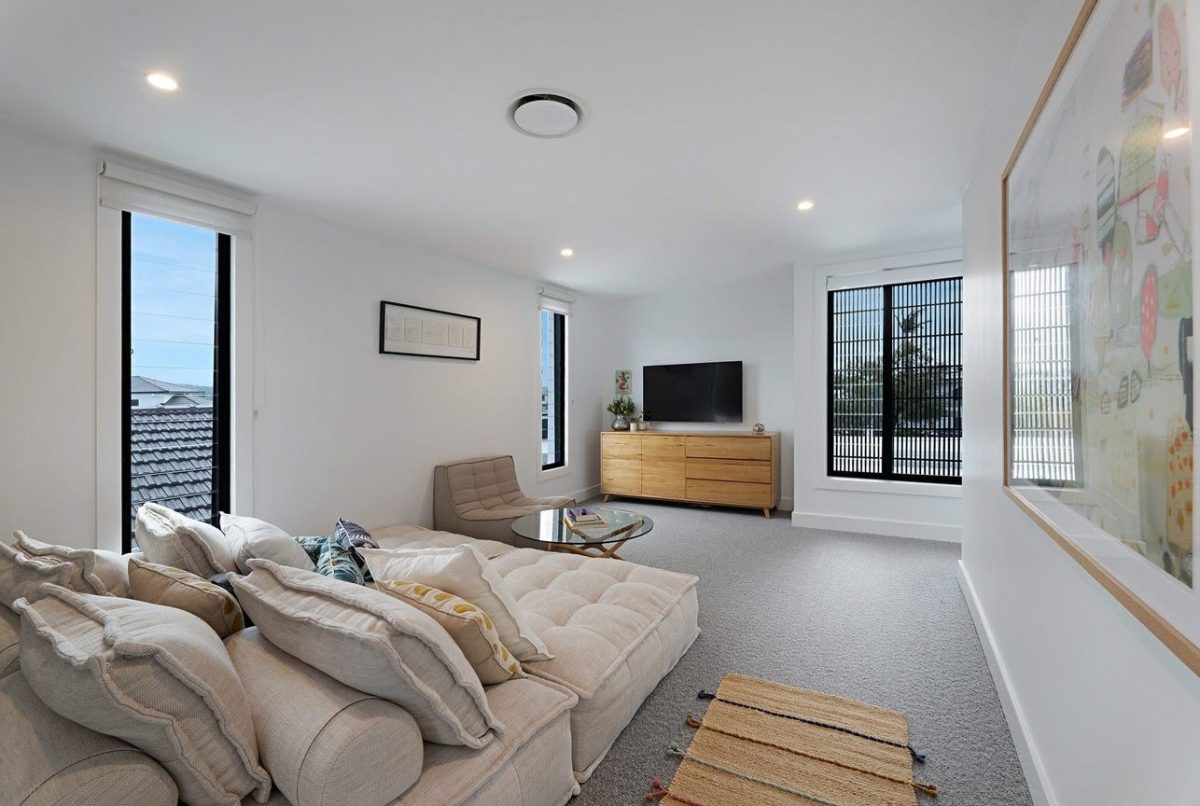 First floor lounge at 28 Kookaburra Court, Sorrento, featuring a relaxing ground level couch, TV cabinet with wall-mounted TV, and louvre windows