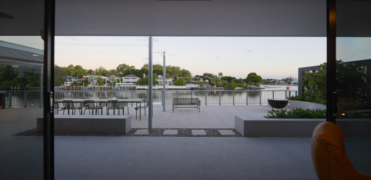 Back terrace view at 28 Kookaburra Court, Sorrento, from the dining room, featuring open sliding doors, concrete and tiled terrace, canal views, and open retractable roof
