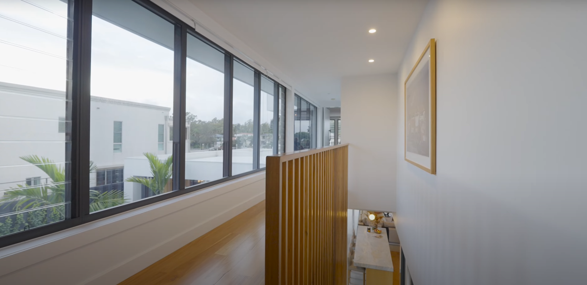 Upper level hallway at 28 Kookaburra Court, Sorrento, viewed from the top of the staircase, featuring timber battens, balustrade screen, fixed glass and louvre windows, and leading to the master bedroom