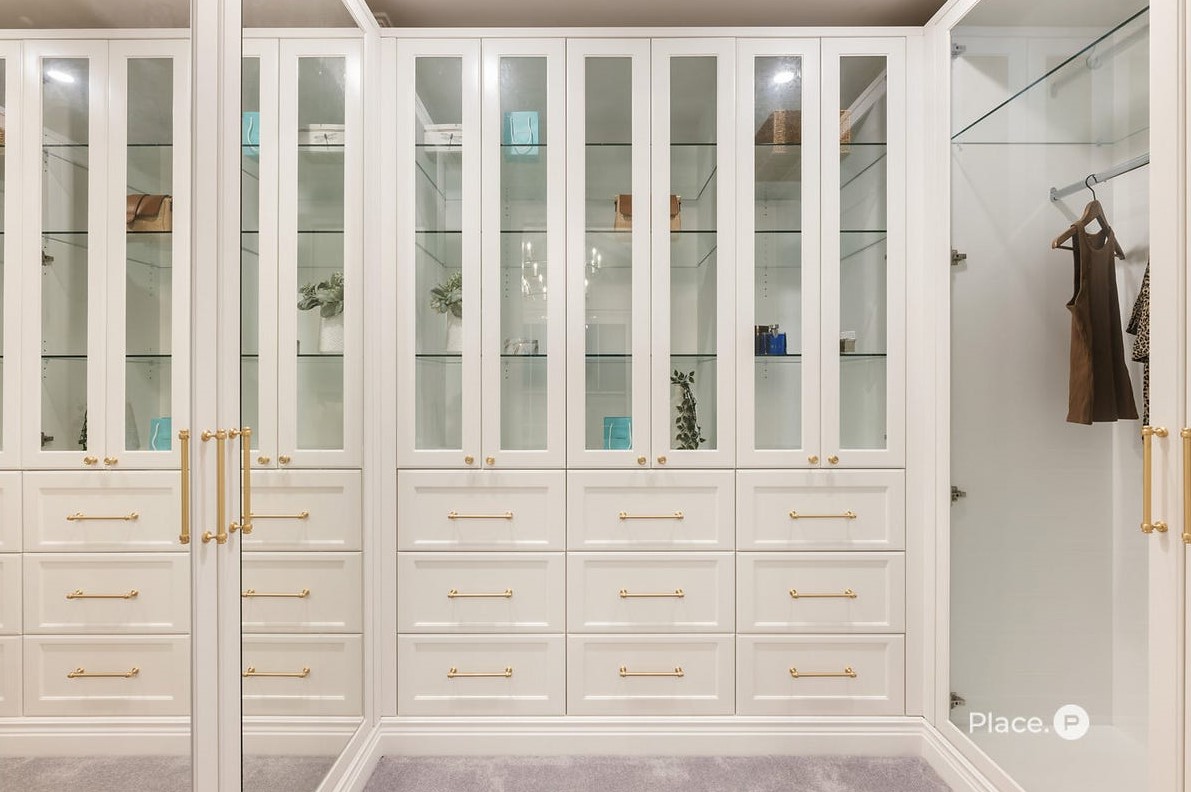 Walk-in robe at 63 Oateson Skyline Drive, Seven Hills, featuring full-height cabinetry, drawers, shelving, mirrors, gold handles and knobs, glass insert panels on the cabinet doors, and shaker style drawer face panels.