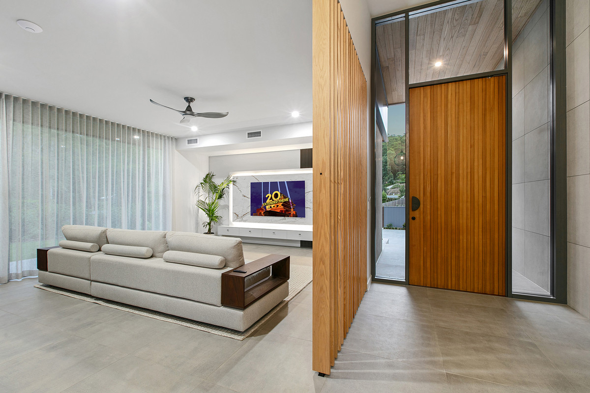 Front entry and media room at 74 Anning Road, Forest Glen, featuring a stone-backed TV wall and custom timber door.