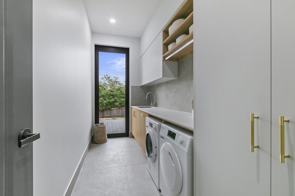 Fully equipped laundry at 74 Anning Road, Forest Glen with sink, cupboards, benchtop, linen cupboard, and drying courtyard view